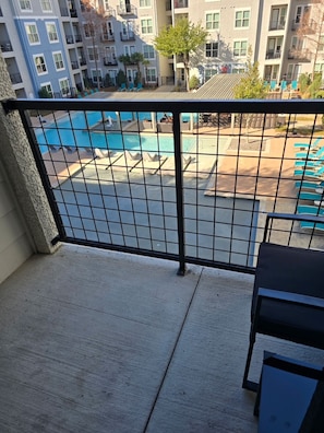 Ein Balkon mit Blick auf ein Schwimmbecken und Liegestühle.