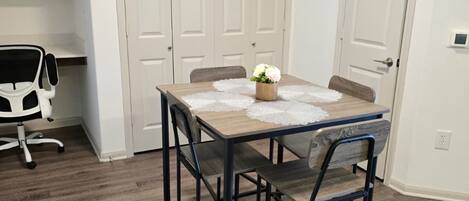 Un comedor con una mesa, sillas y un pequeño centro de mesa con una planta.