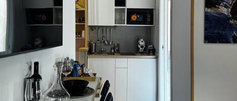 A modern kitchen with white cabinets, a dining table with chairs, and a coffee machine.