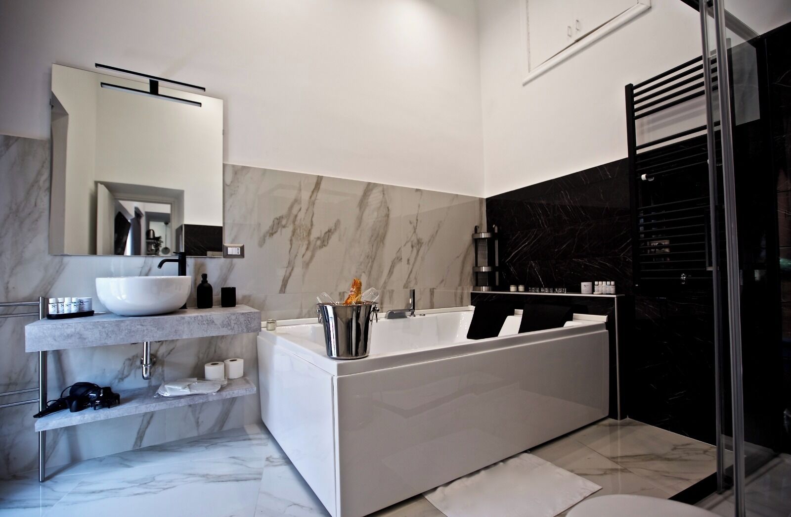 A modern bathroom with a white sink, a large bathtub, and a glass shower enclosure.