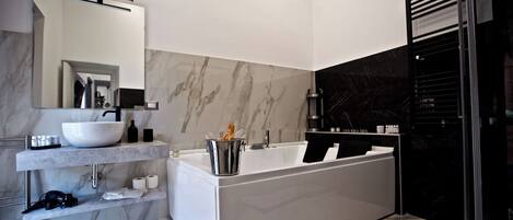 A modern bathroom with a white sink, a large bathtub, and a glass shower enclosure.