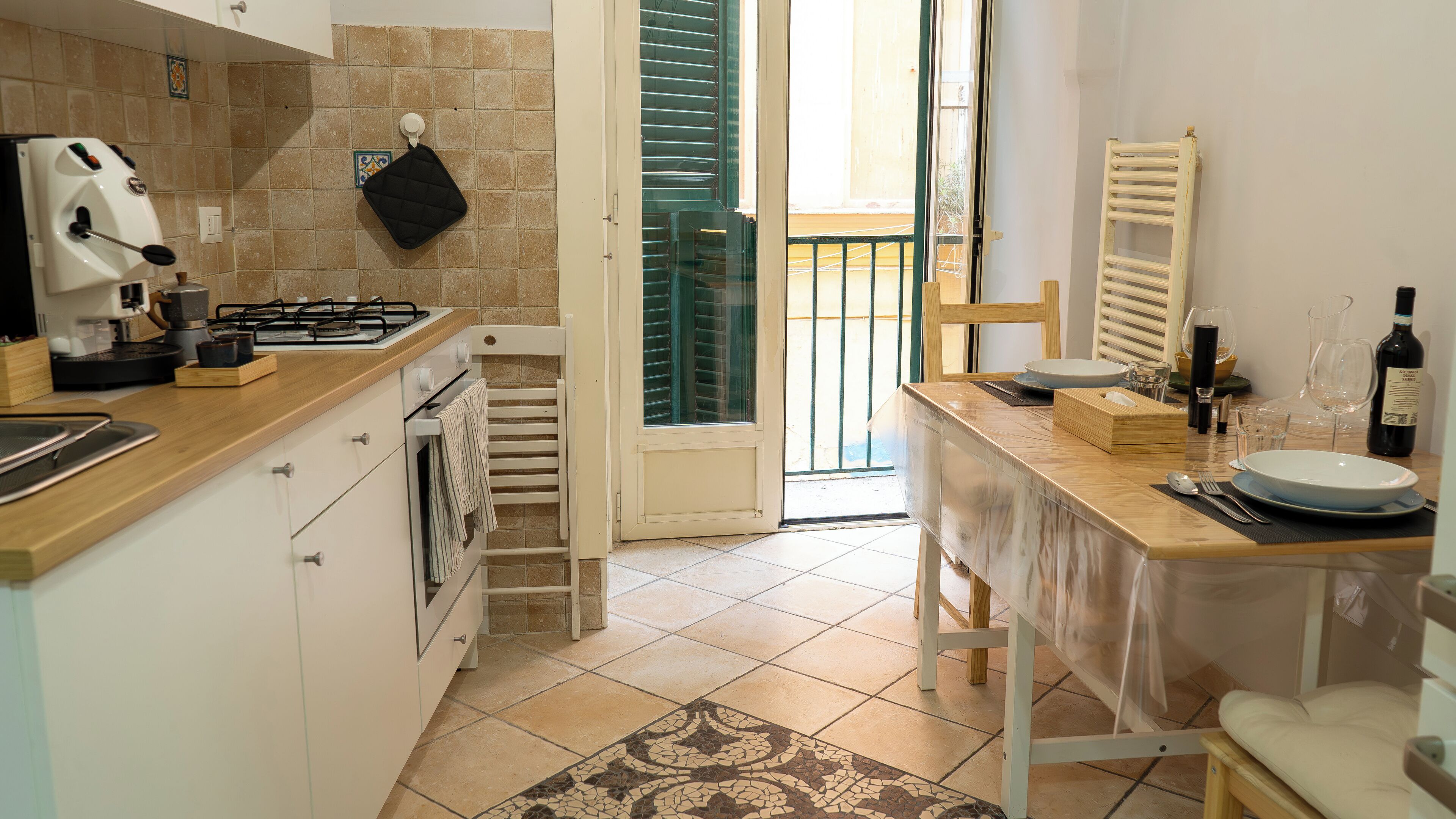 A kitchen with a gas stove, oven, and a dining area with a table set for two.