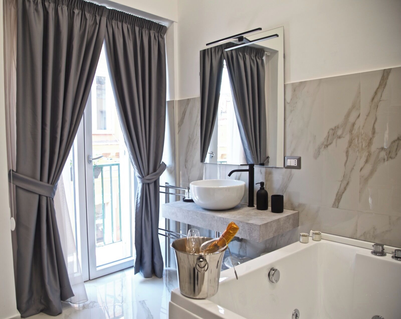A modern bathroom with a large bathtub, a vessel sink, and a glass of champagne.