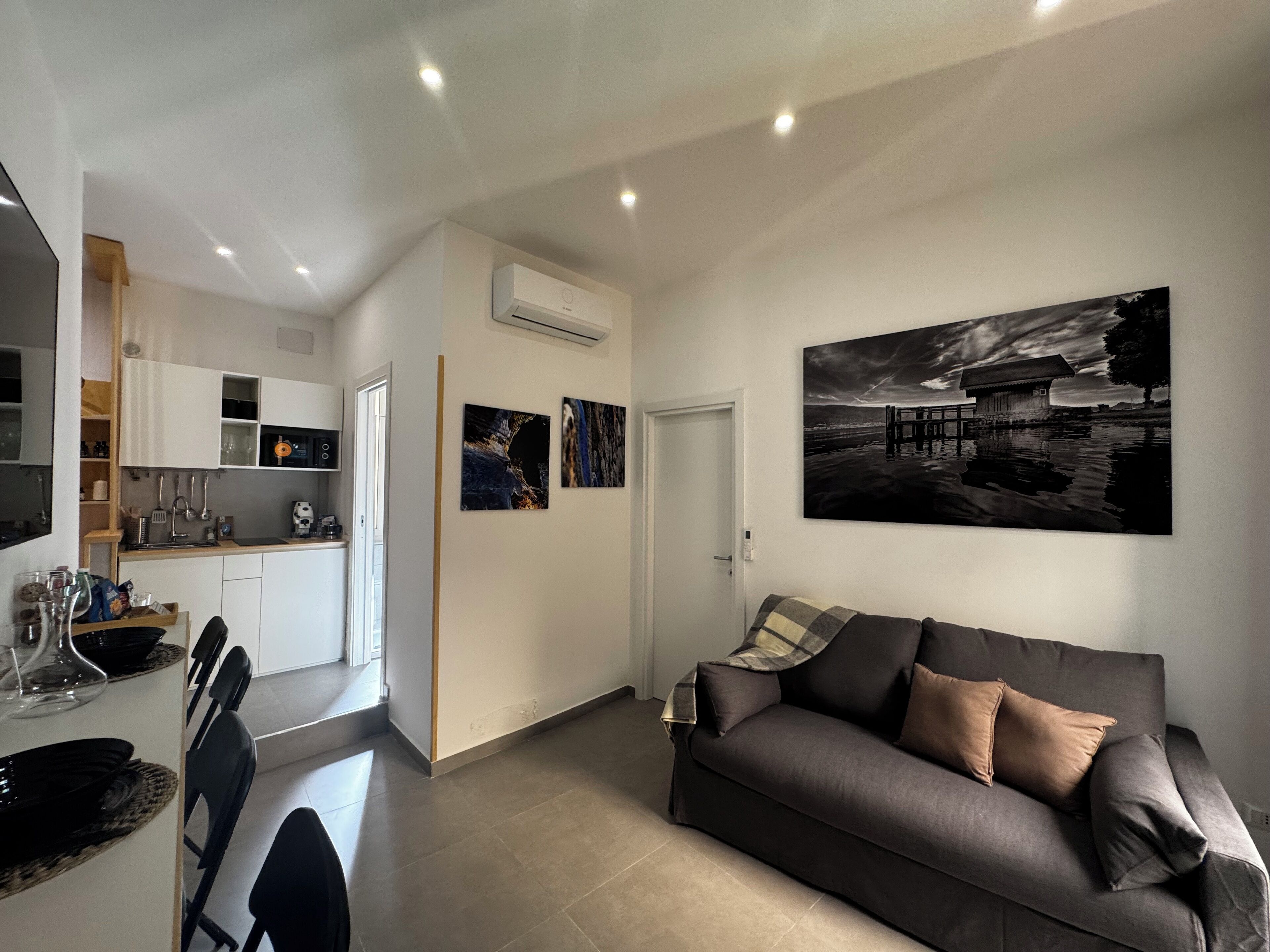 Un soggiorno moderno con un divano grigio scuro e un quadro raffigurante un ponte.