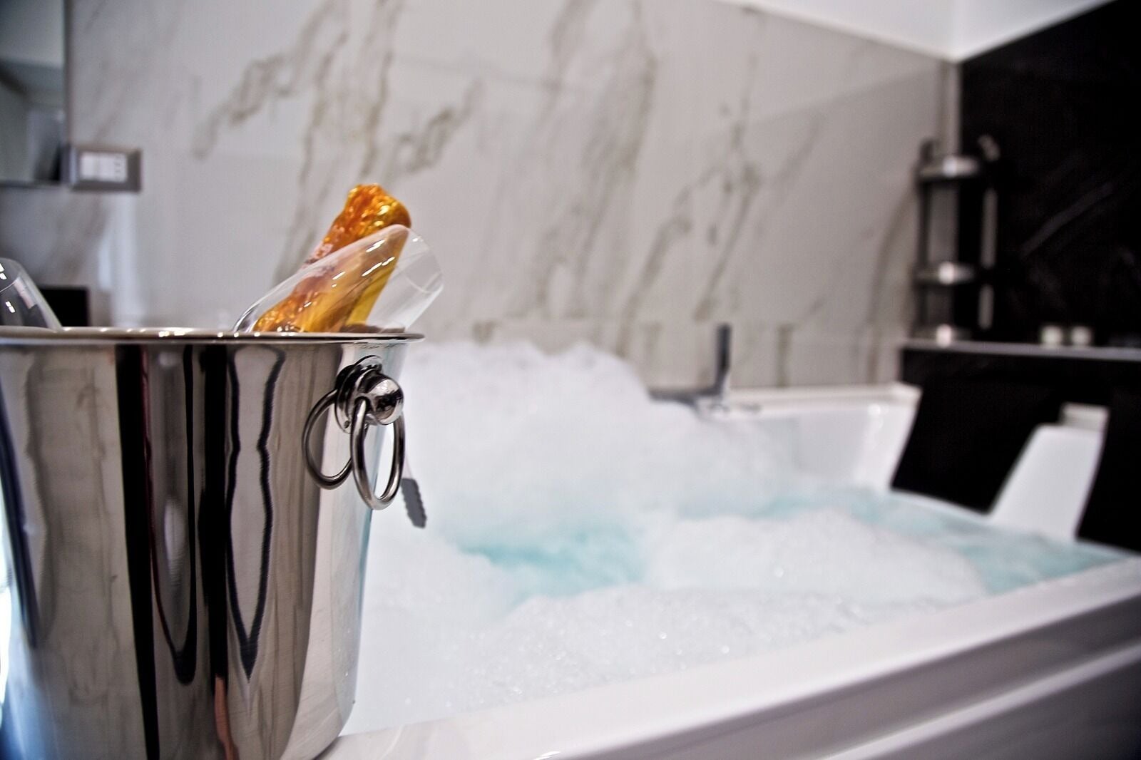 A hot tub with a metal bucket containing a bottle and a lemon.