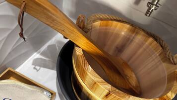 A wooden bowl with a rope handle, a small wooden box with a zipper, and a metal faucet in the background.