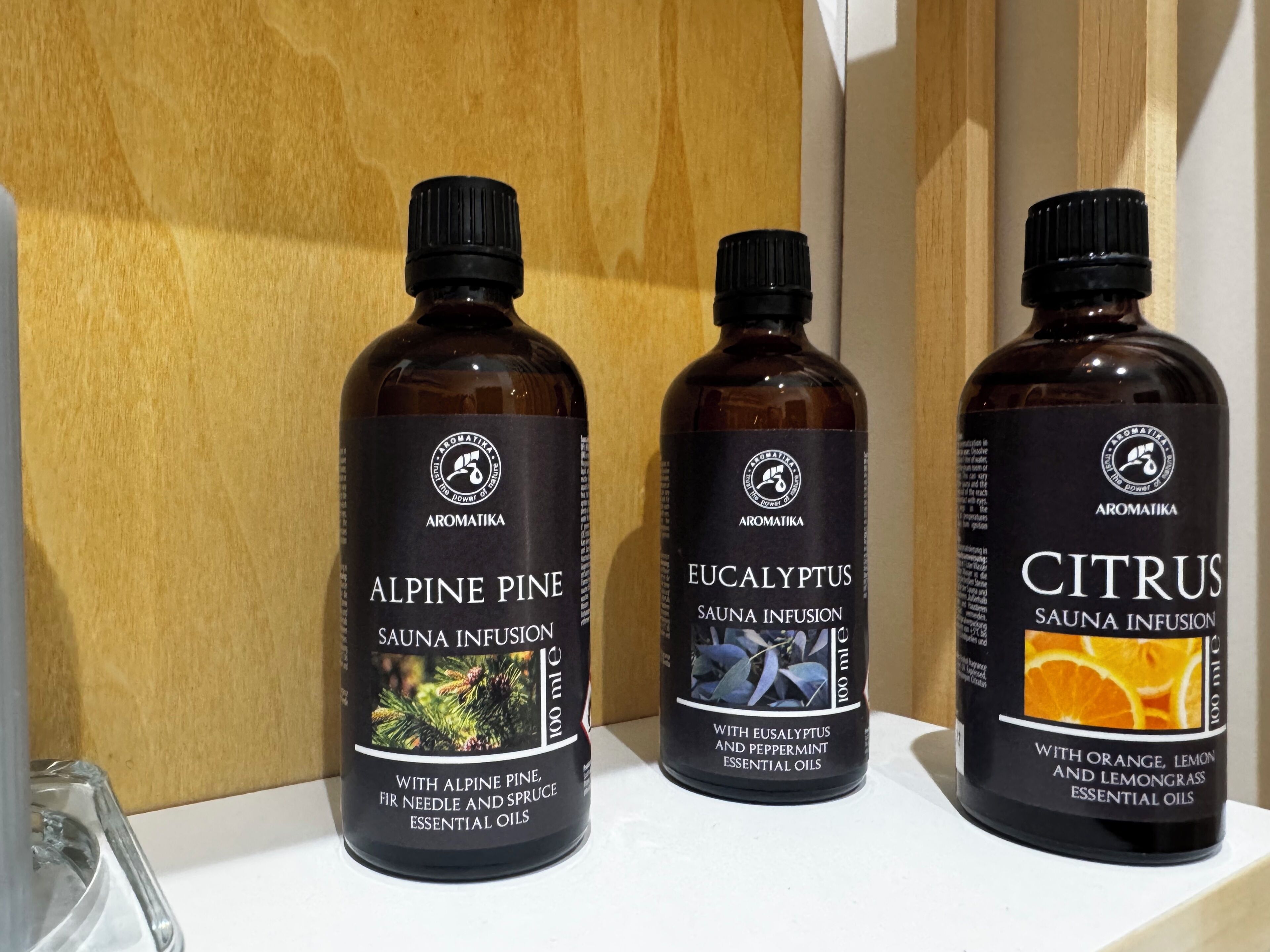 Three bottles of essential oils labeled Alpine Pine, Eucalyptus, and Citrus on a shelf.