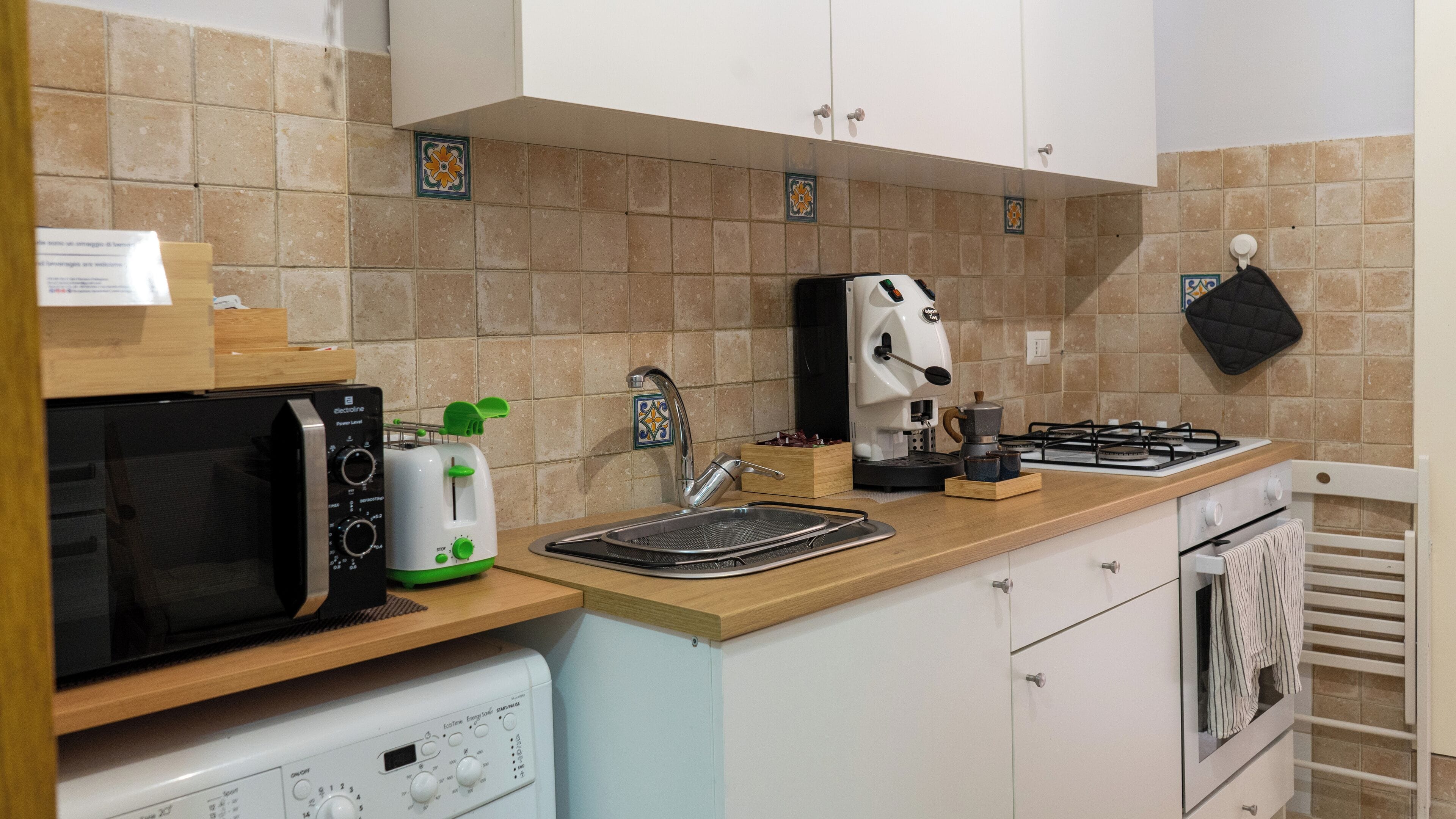 A kitchen with a microwave, toaster, coffee maker, sink, and stove.