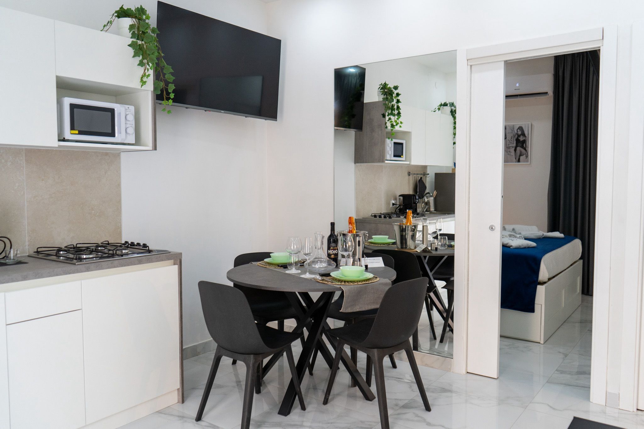 A modern kitchen with a dining area, a flat-screen TV, and a small microwave.