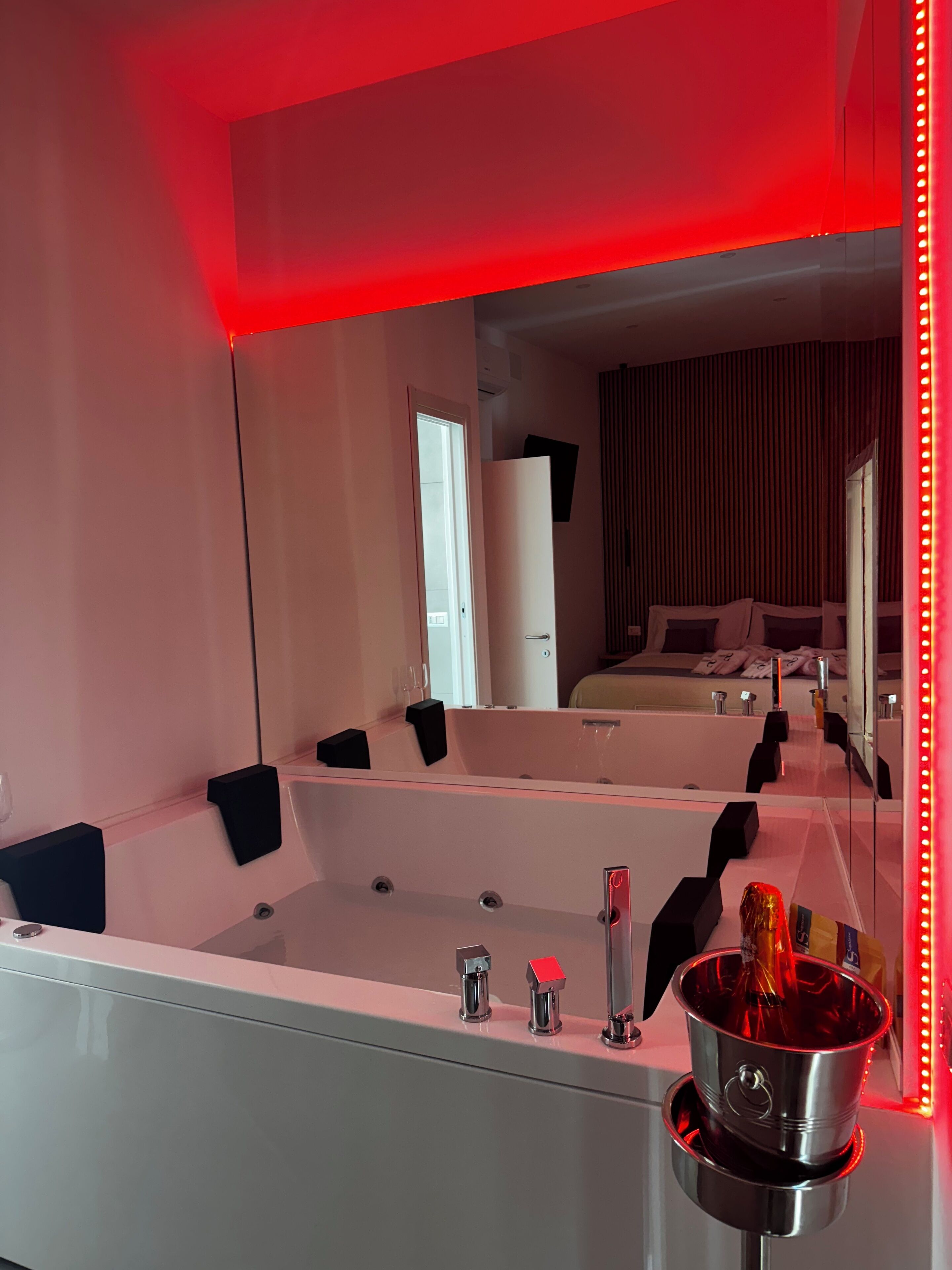 A modern bathroom with a large mirror, a bathtub, and a sink.