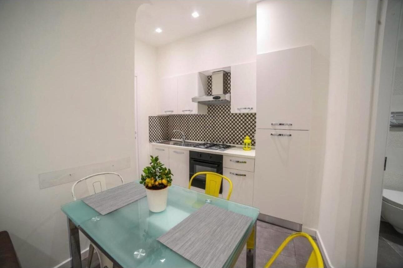 A compact kitchen with white cabinets, a black and white backsplash, and a gas stove.