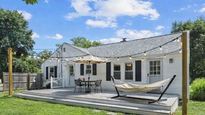 A house with a covered patio, outdoor furniture, and a hammock. - Narragansett Coastal Retreat- minutes to Beach & Pond (Narragansett)