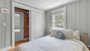 A bedroom with a bed, a window, a door, and a wooden closet. - Narragansett Coastal Retreat- minutes to Beach & Pond (Narragansett)
