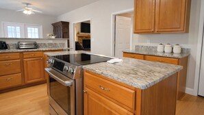A kitchen with wooden cabinets, a stainless steel stove, a granite countertop, and a ceiling fan.