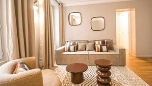 Ein Wohnzimmer mit einer Couch, zwei Couchtischen und einem gemusterten Teppich.