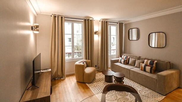 Ein modernes Wohnzimmer mit Sofa, Sessel und Fernsehschrank.