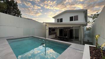 A modern house with a swimming pool, a covered patio, and a two-story structure.