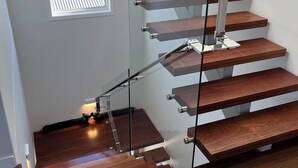 Una escalera moderna con barandillas de vidrio y escalones de madera.