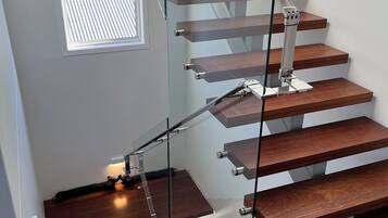 A modern staircase with glass railings and wooden steps.