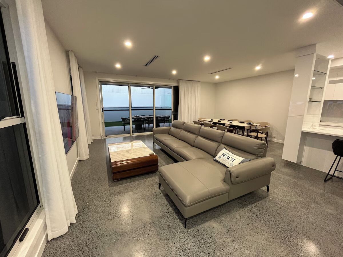 A modern living room with a large sectional sofa, a coffee table, and a dining area with chairs.
