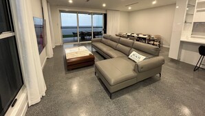 Una sala moderna con un sofá seccional grande, una mesa de centro y un comedor con sillas.