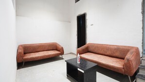 Une pièce avec deux canapés en cuir marron, une table basse noire et un mur blanc orné d’une petite fenêtre.