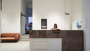 Un comptoir d’accueil avec une pancarte indiquant la zone d’accueil, un canapé et un panneau indiquant la présence d’un système de vidéosurveillance sur le mur.