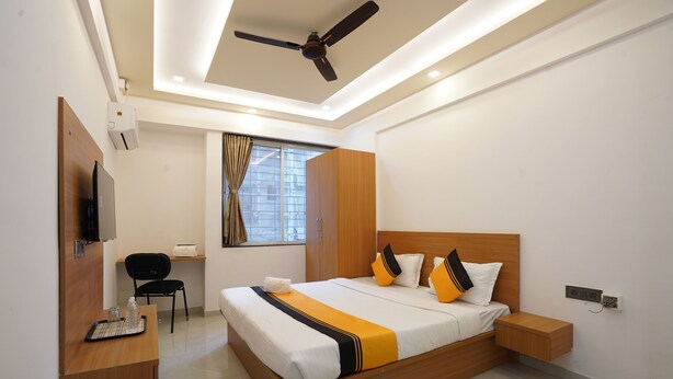 Une chambre d’hôtel moderne équipée d’un grand lit, d’un bureau avec une chaise, d’une télévision et d’un ventilateur de plafond.