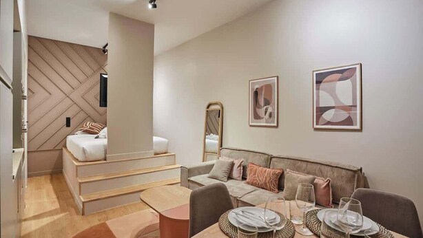 Ein moderner, gut beleuchteter Raum mit Essbereich, einer Couch und einer Treppe.