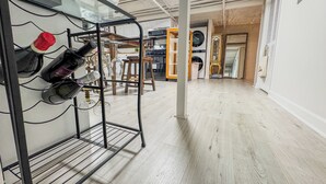 Een hal met een schoenenrek, een wasmachine en een houten vloer.