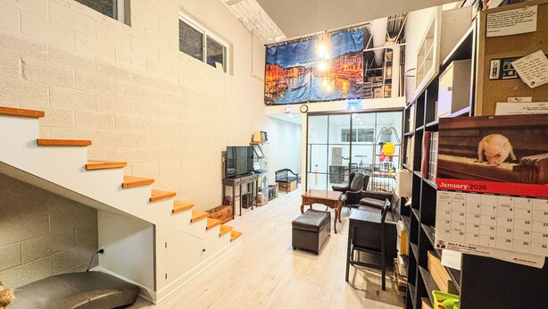 Een ruime woonkamer met een trap, een televisie en een kalender aan de muur.