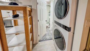 Een wasserette met een wasmachine, droger en een houten plankunit.