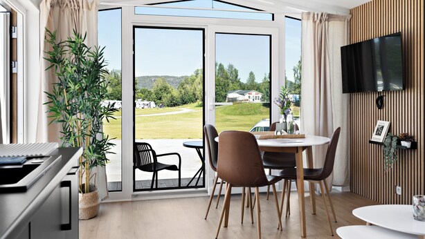 Un espace de restauration moderne offrant une vue sur un paysage verdoyant grâce à de grandes portes vitrées.