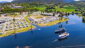 Vue aérienne d’une zone au bord du lac, avec un quai pour bateaux, un parking où sont stationnés des camping-cars et un petit bâtiment.