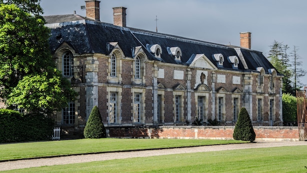 A large, historic building with a symmetrical facade, multiple chimneys, and a well-maintained lawn. - Pavillon de l'Orangerie room (La Ferté-Saint-Aubin)