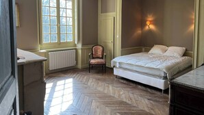 A bedroom with a large bed, a chair, a desk, and a window with a view of trees. - Pavillon de l'Orangerie room (La Ferté-Saint-Aubin)
