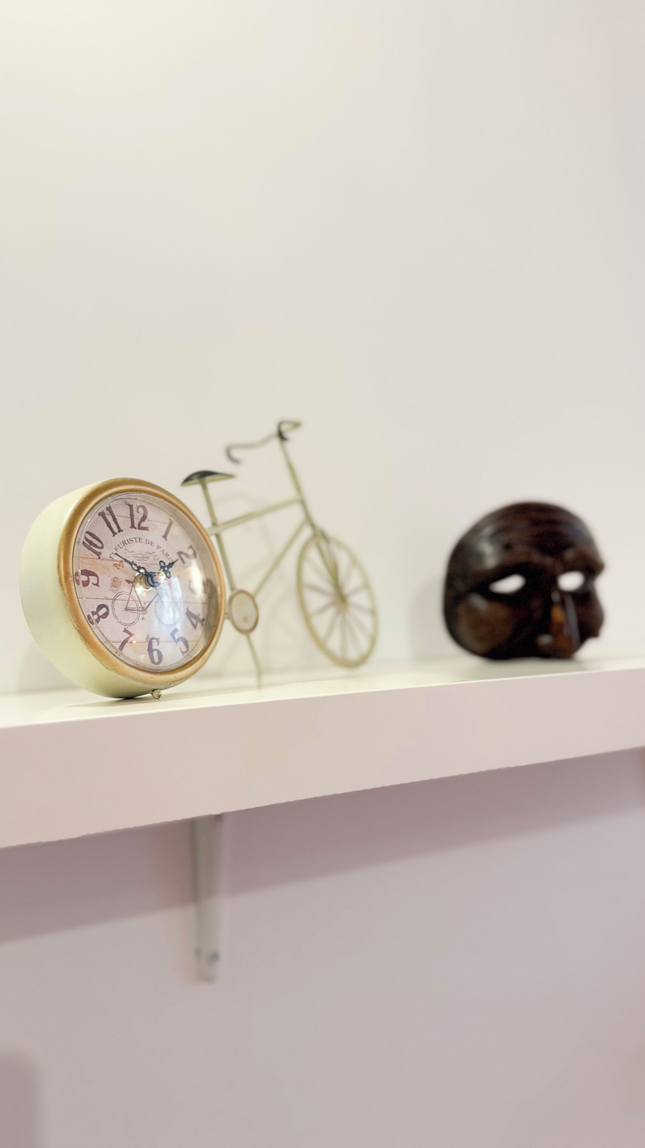 A shelf with a vintage-style clock, a bicycle silhouette, and a helmet.