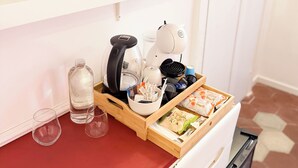 Une petite cuisine équipée d’une machine à café, d’une bouilloire et d’un espace de rangement pour les aliments.