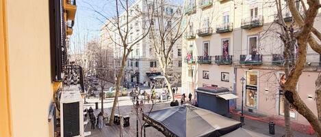 Un patio con asientos al aire libre, un edificio con balcones y cielo despejado.