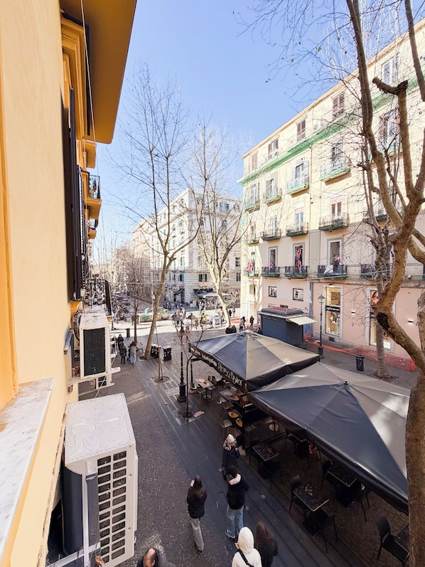 A courtyard with outdoor seating, a building with balconies, and a clear sky. - Suite Scarlatti (Naples)