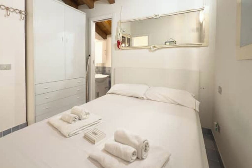 Une chambre d’hôtel avec un lit, un grand miroir et une armoire.