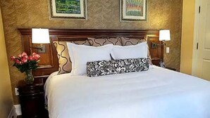 Ein Hotelzimmer mit einem großen Bett, zwei Nachttischen, einem Schminktisch und zwei gerahmten Bildern an der Wand.