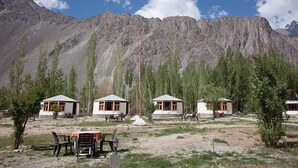 A remote mountain lodge with four cabins, each featuring a small porch and a dining area. - Nubra Sarai (Hunder)