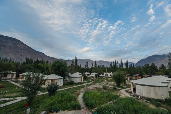 A cluster of yurts in a mountainous area with a clear sky. - Nubra Sarai (Hunder)