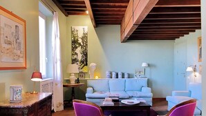 A cozy living room with a wooden ceiling, a light blue sofa, two purple chairs, and a coffee table. - Luxury Trastevere apartment (Roma)