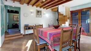 A dining area with a wooden table and chairs, a colorful tablecloth, and a wooden ceiling with exposed beams. - Luxury Trastevere apartment (Roma)