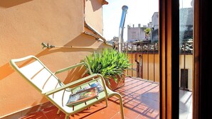 A balcony with a chair, a potted plant, and a newspaper. - Luxury Trastevere apartment (Roma)