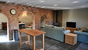 Ein Wohnzimmer mit Kamin aus Backstein, einem Holztisch, einer Couch und einem Fernseher.