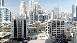 A high-rise hotel with multiple floors, a marina with boats, and a river in the background. - StayShort - Studio in Marina that Sleeps 3 with a Perfect City View (Dubai Marina)