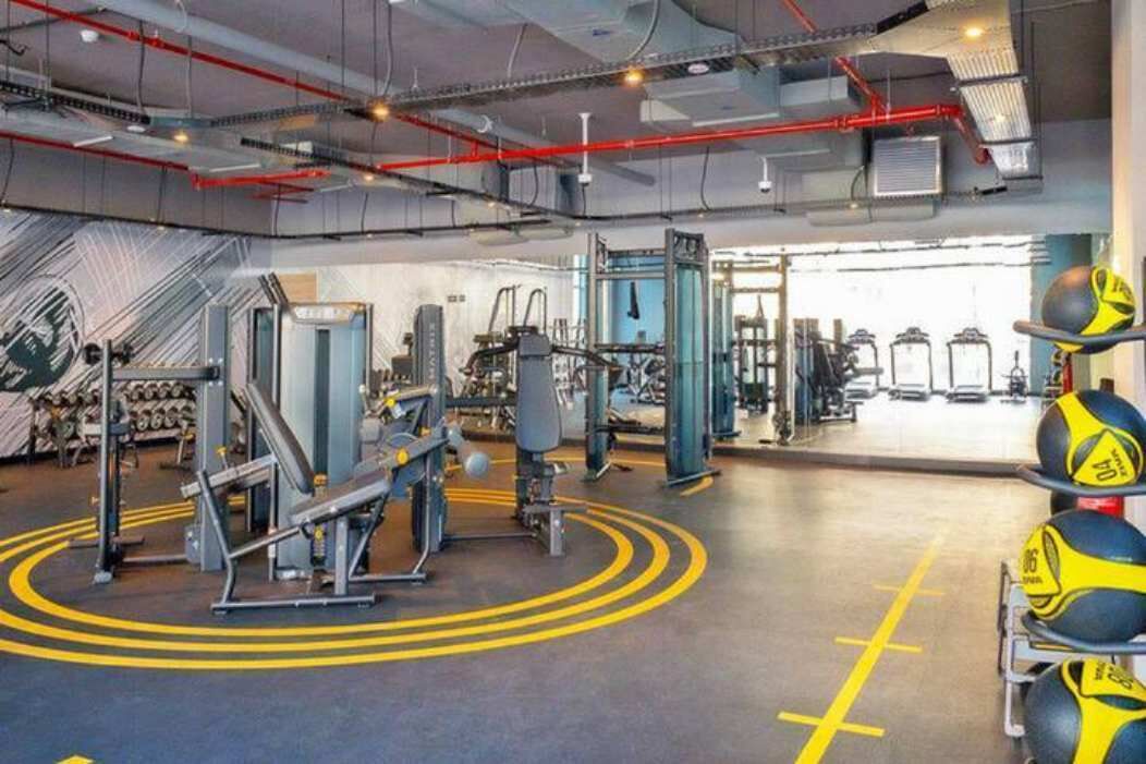 Une salle de sport équipée de matériel d’exercice, de supports pour les poids et d’un mur orné d’un motif circulaire.